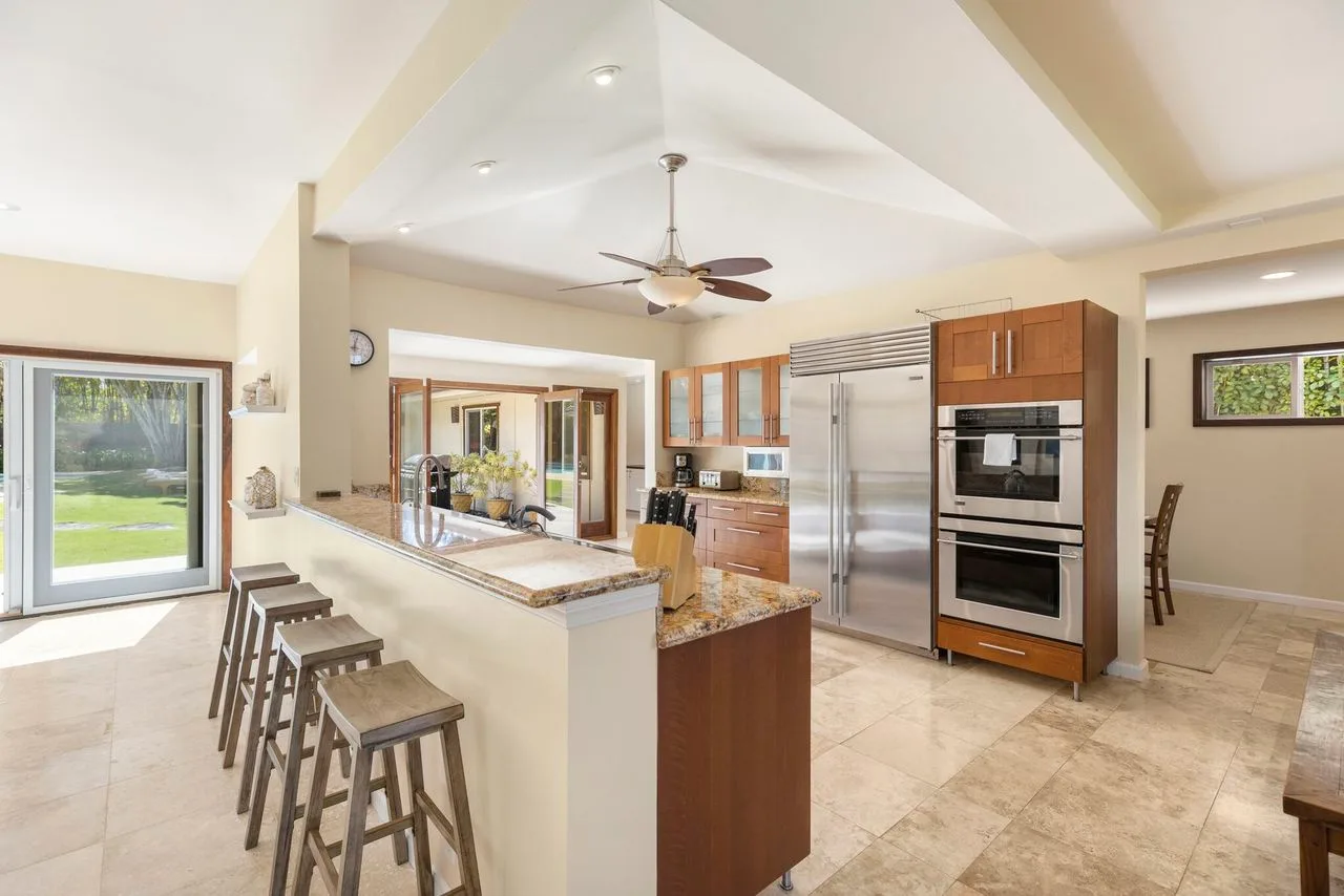 A bright kitchen with a central island, stainless steel appliances, and an open dining area.