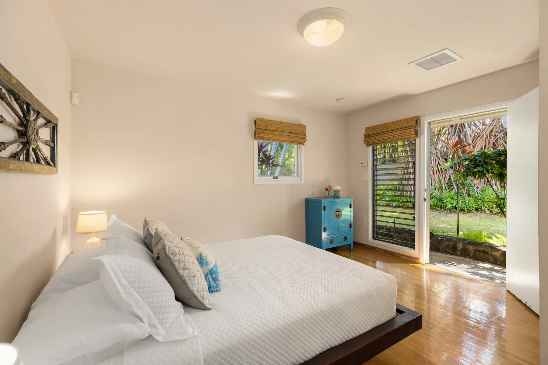 A bedroom with a bed, a blue cabinet, and glass doors opening onto a garden.