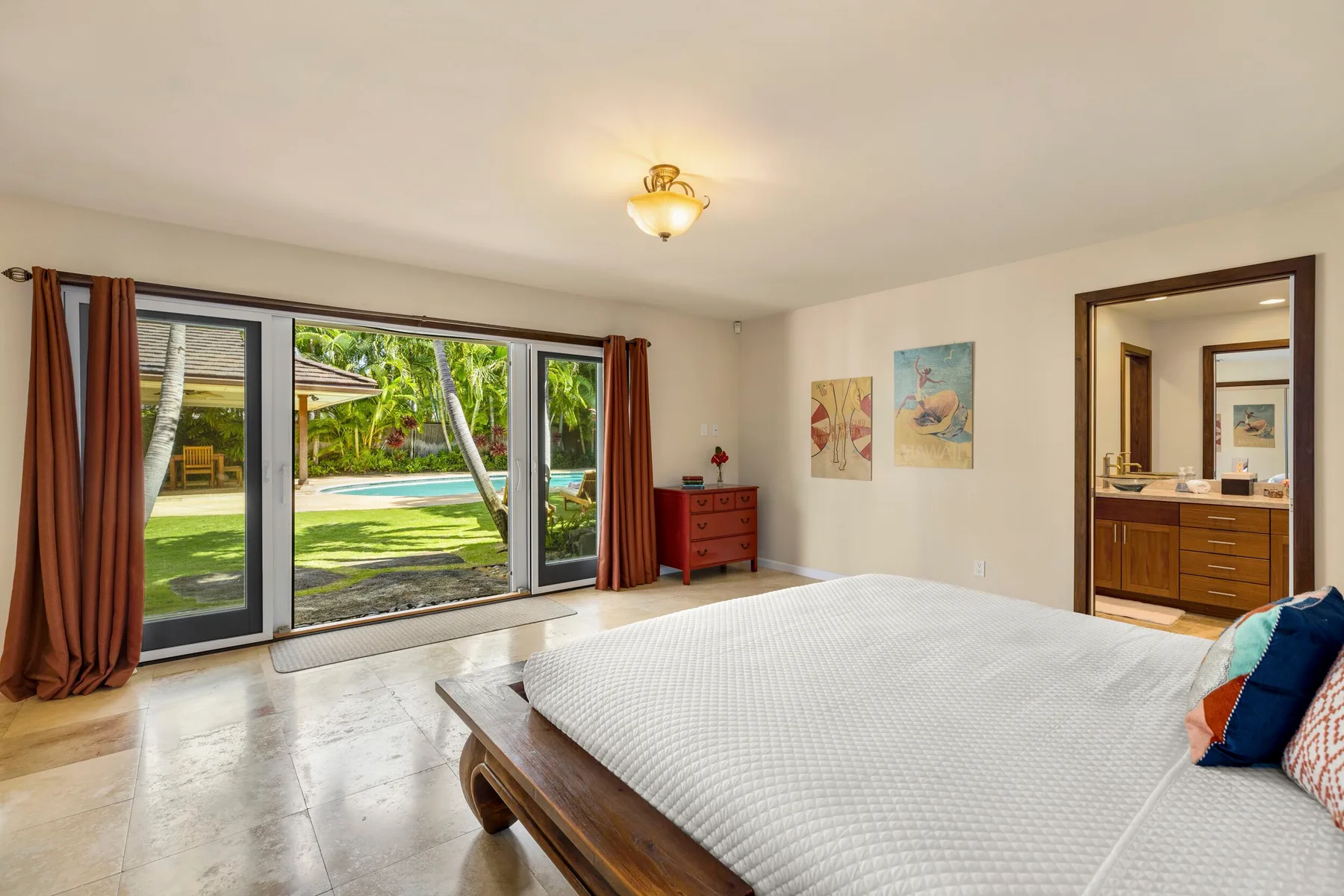 A bright bedroom with a large bed beside glass doors opening onto a garden.