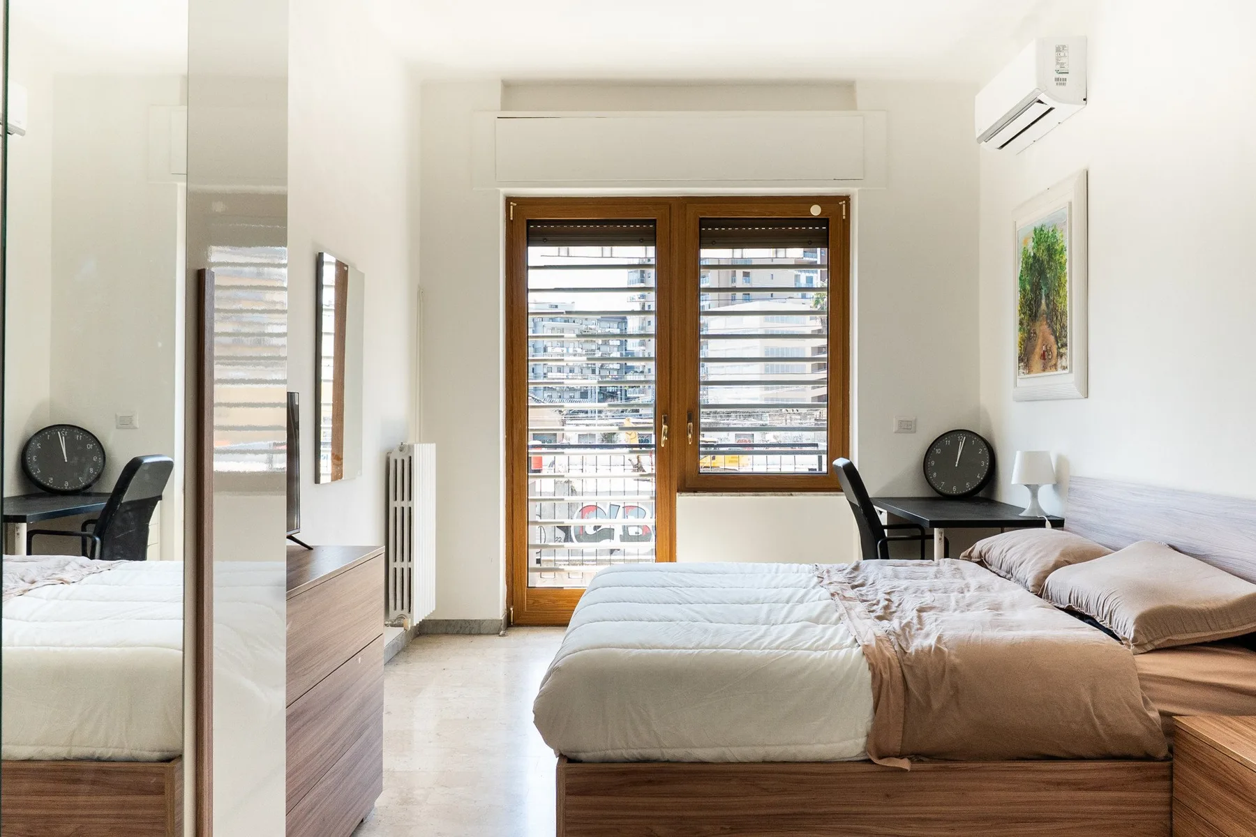 A bright bedroom with a bed and large windows.