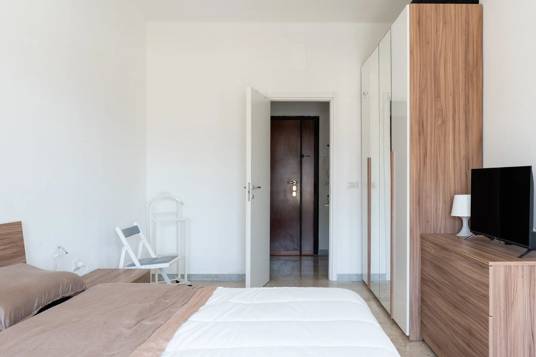 Bedroom with a bed, mirrored wardrobe, and television beside the doorway.