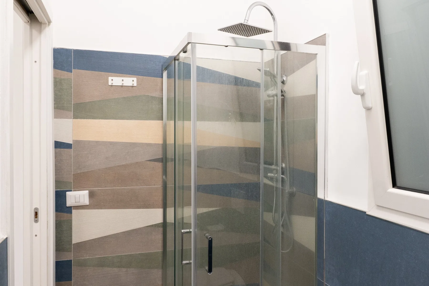 A tiled bathroom with a glass shower and overhead showerhead.