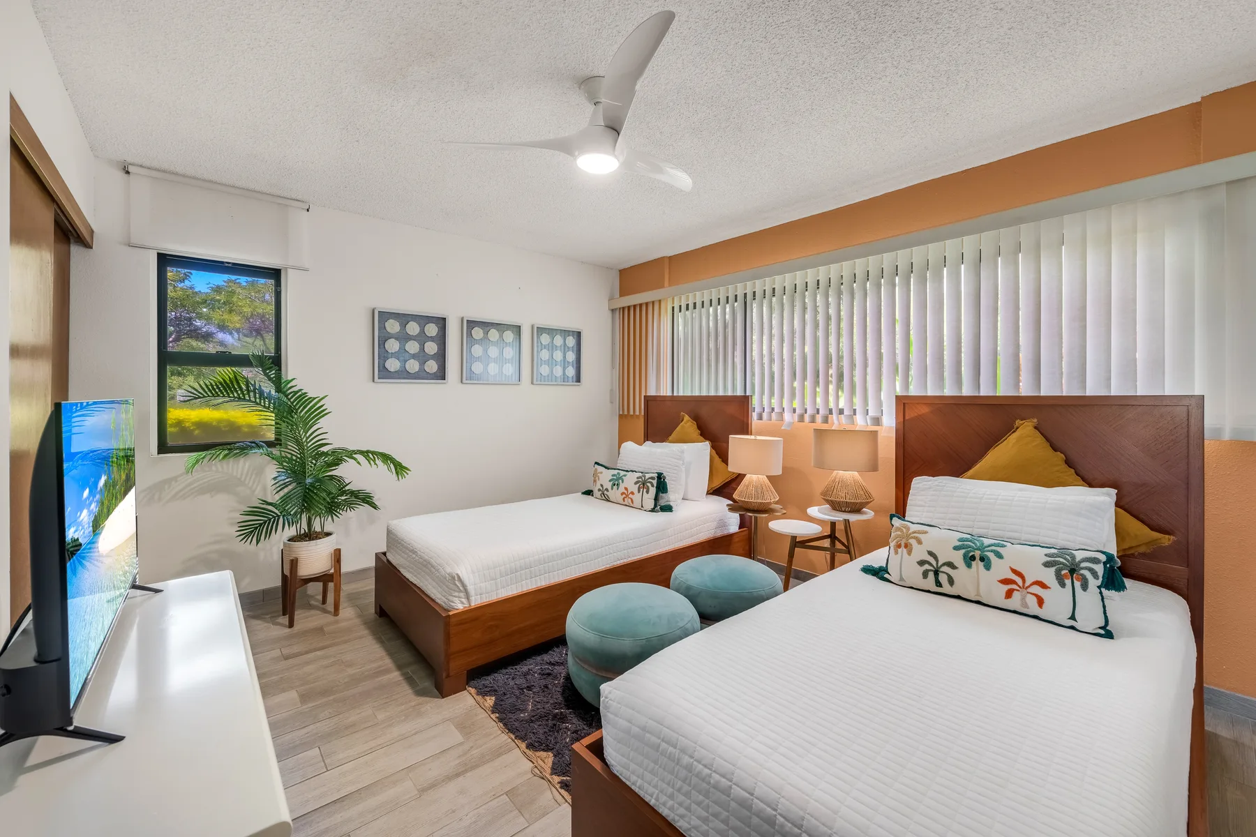 A bedroom with two beds, bedside tables, and vertical blinds.