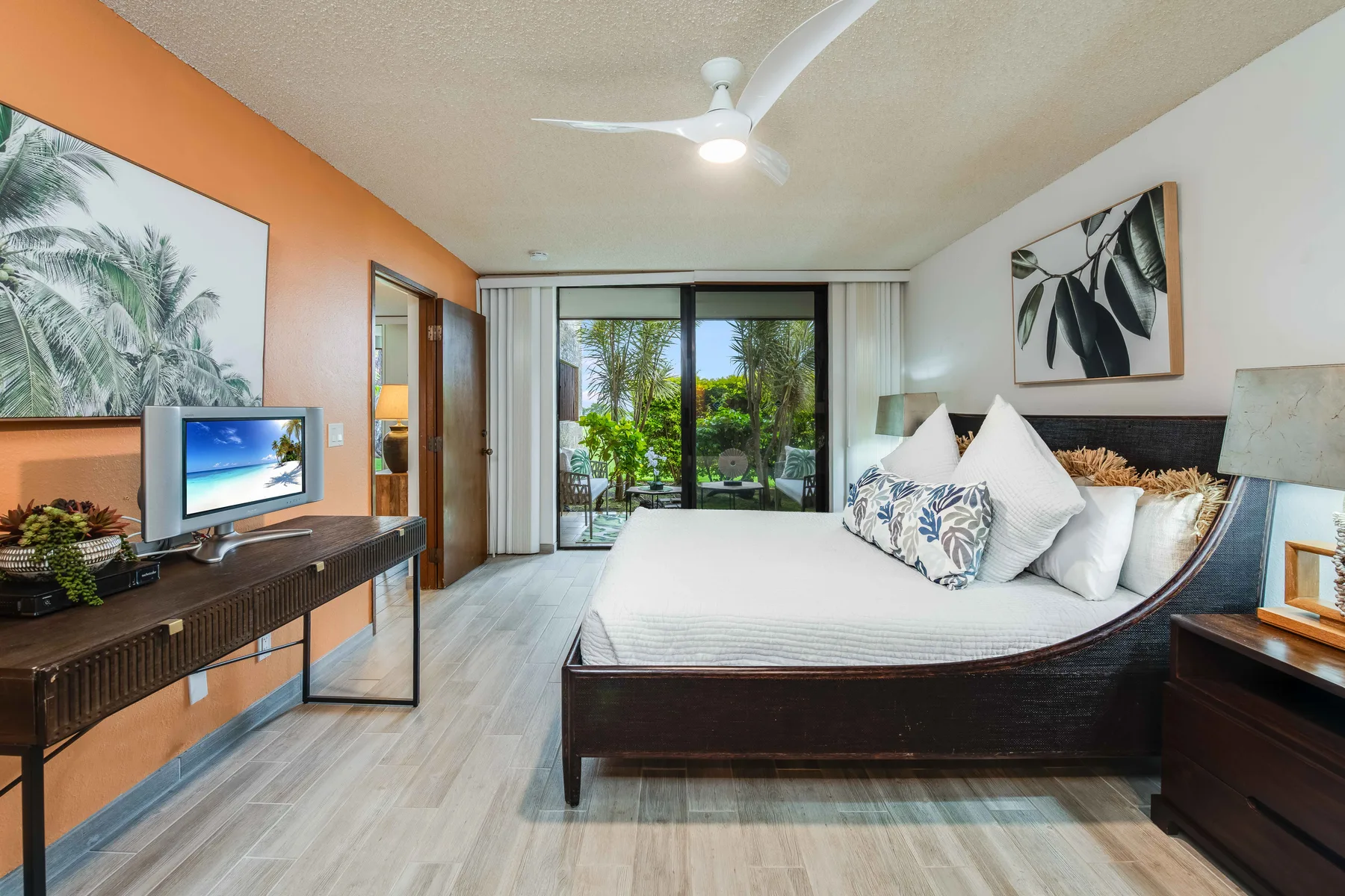 A bedroom with a large bed and sliding glass doors opening onto greenery.