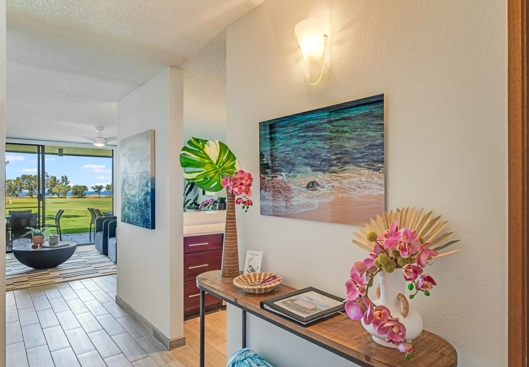 A decorated hallway opens toward a bright living area with sliding glass doors.