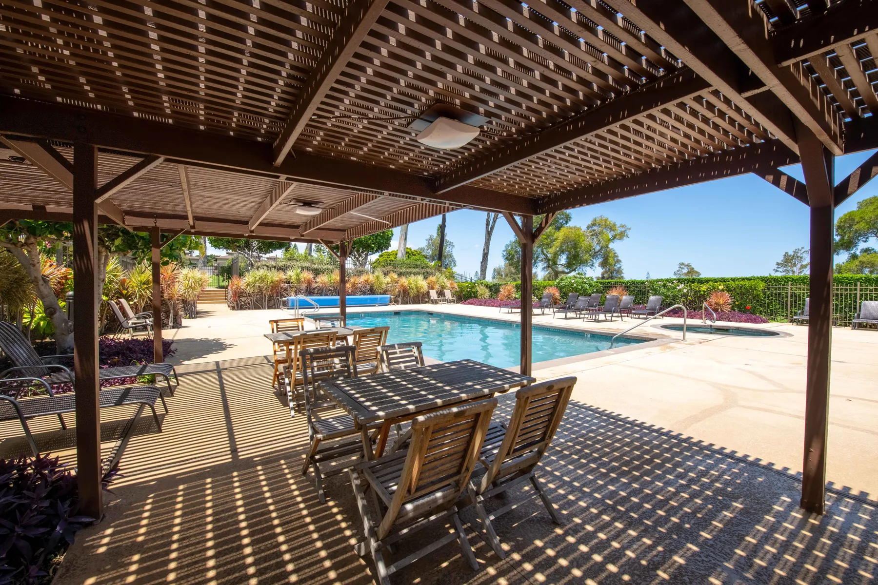 A swimming pool beside a shaded outdoor dining area with tables and seating.