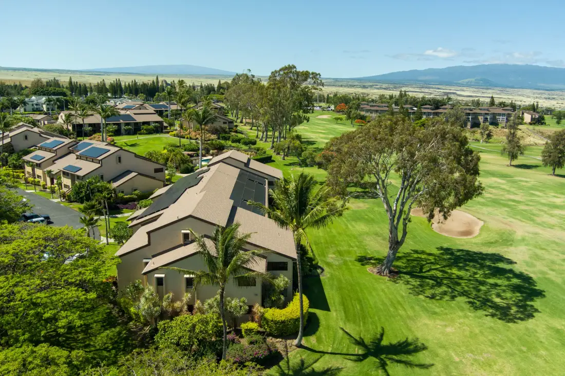 Aerial view of a golf course beside landscaped grounds and low-rise buildings.