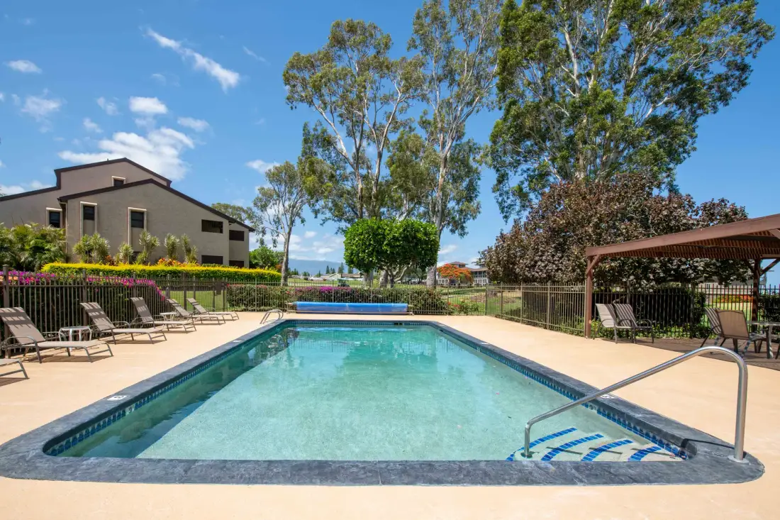 An outdoor swimming pool is surrounded by a paved deck and seating.