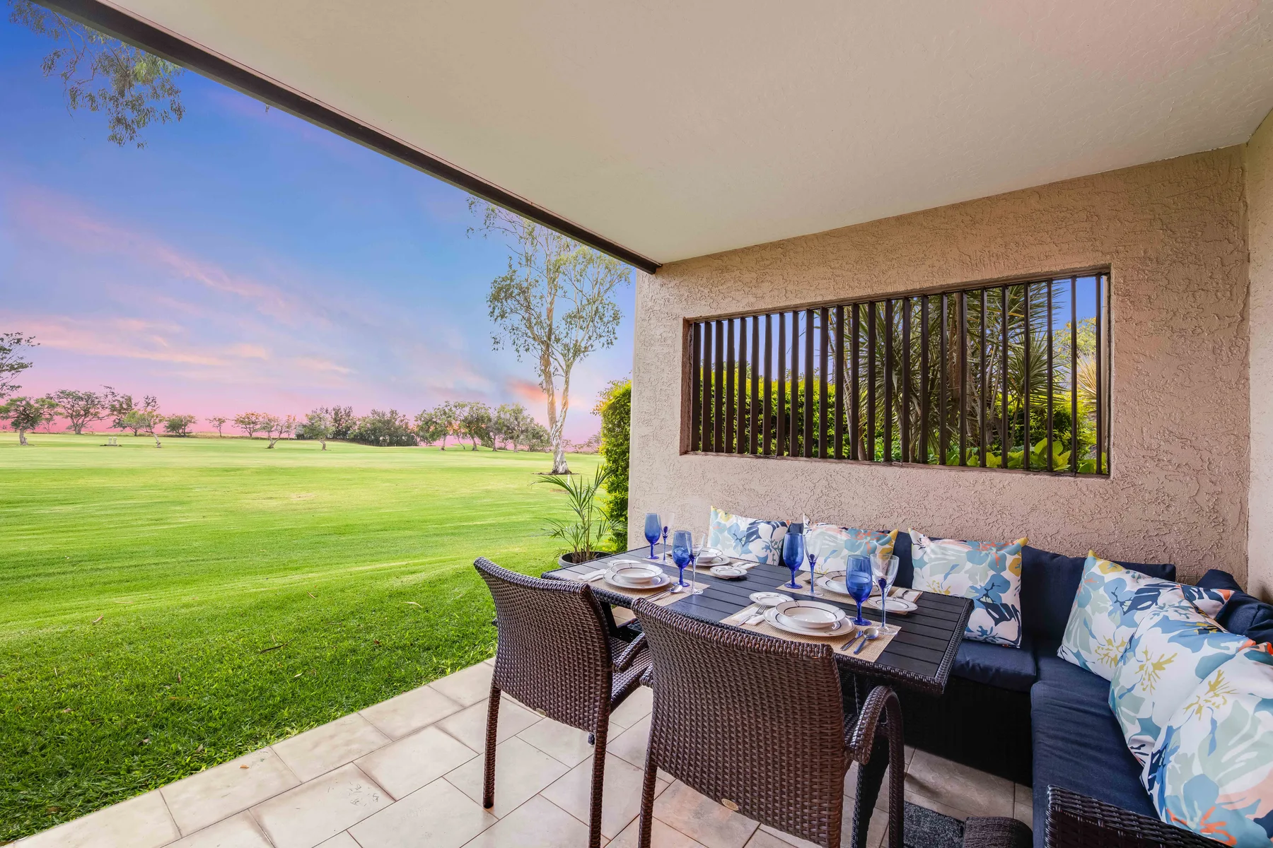 A covered outdoor dining area overlooks a green lawn.