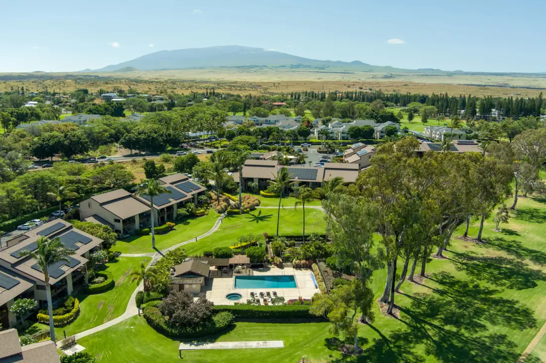 An aerial view of a landscaped resort complex with a swimming pool and surrounding greenery.