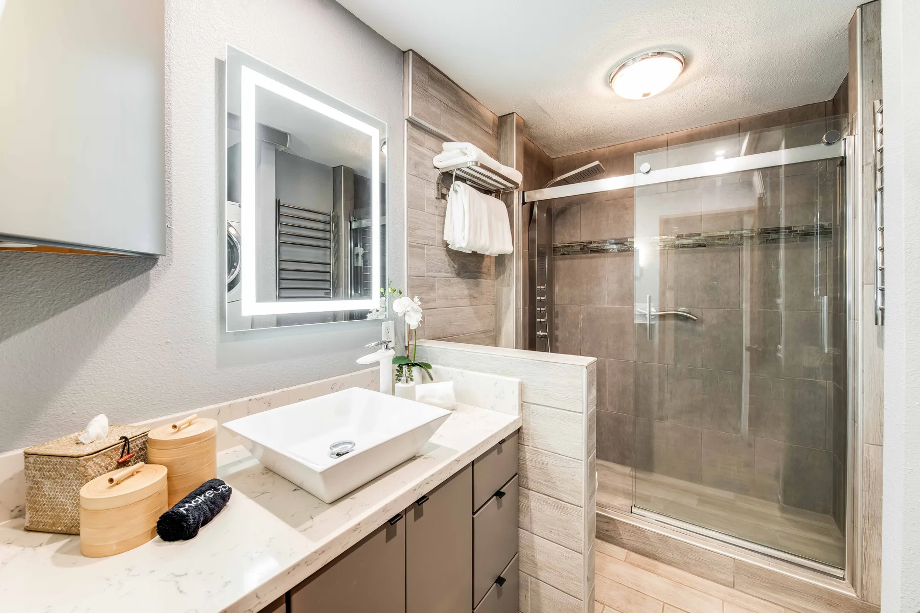 A bathroom with a glass-enclosed shower and a sink vanity.