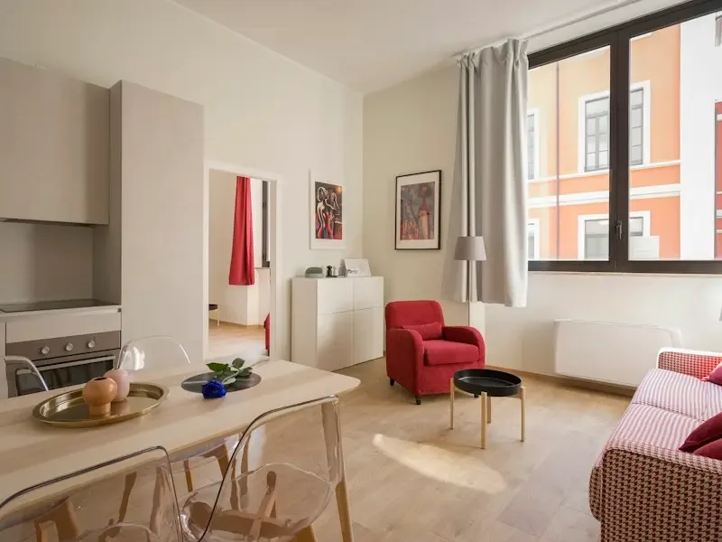Una luminosa sala de estar y comedor con un sillón rojo junto a una ventana grande.