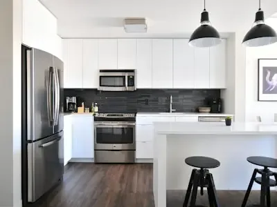Una cocina luminosa con electrodomésticos de acero inoxidable y una barra blanca.