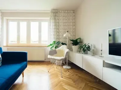 Una sala de estar luminosa con asientos, un televisor y ventanas amplias.