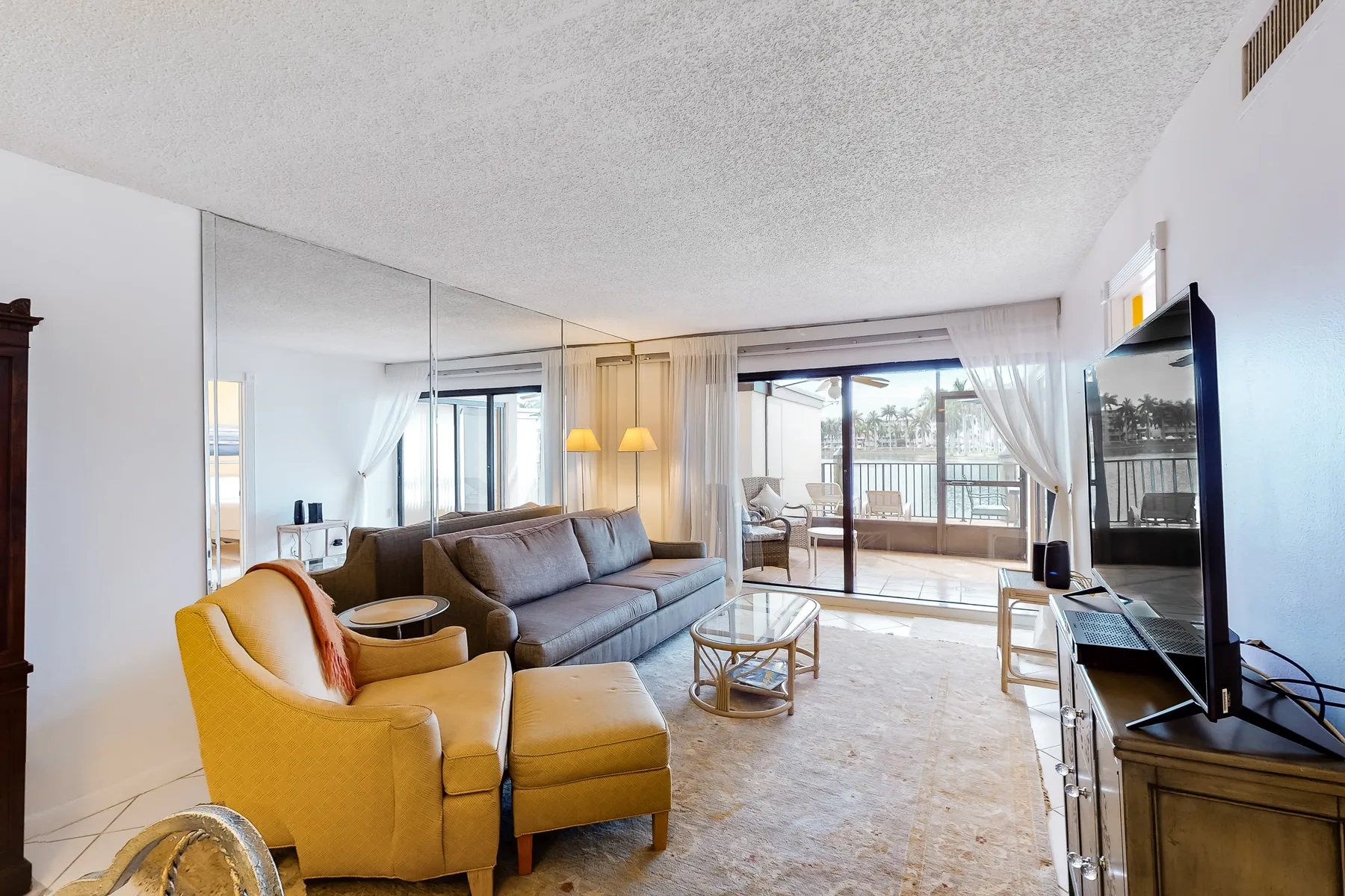 A bright living room with seating, a coffee table, and sliding glass doors.