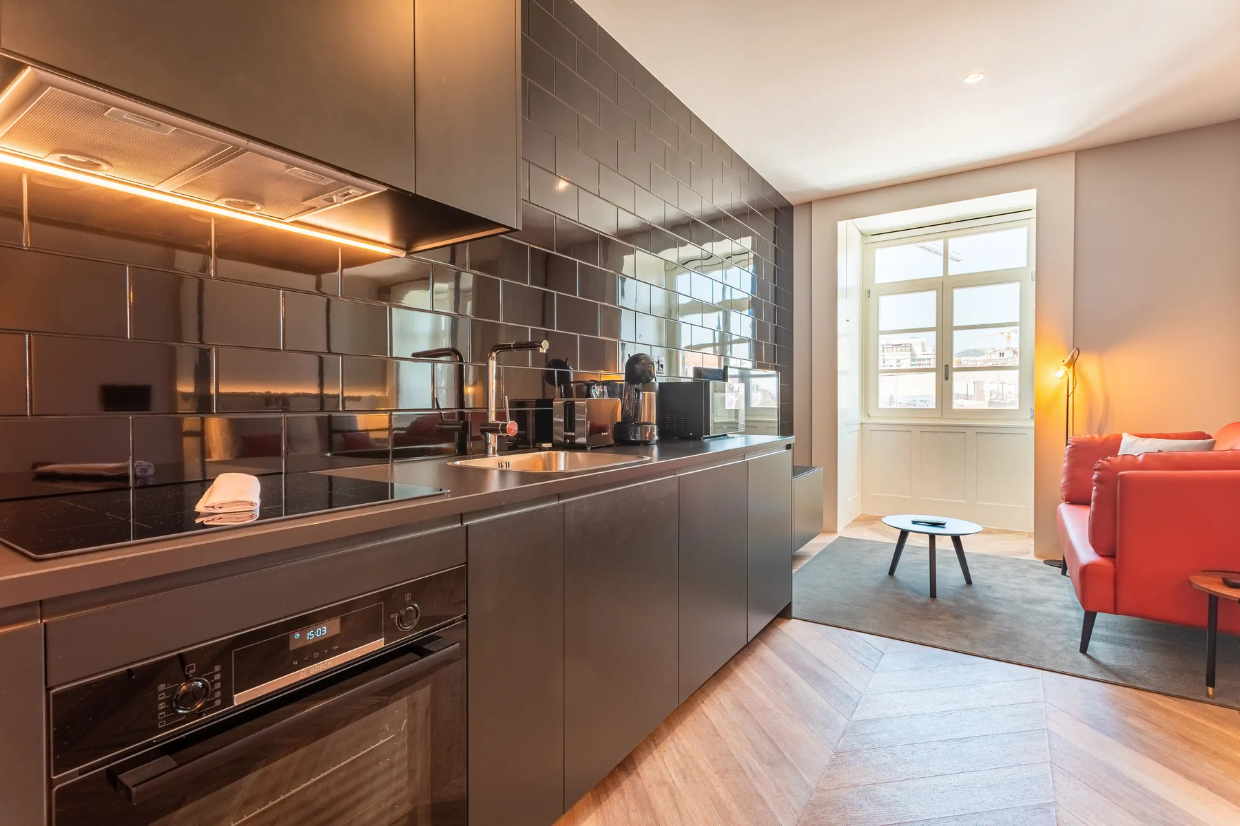 Una cocina moderna se abre a una sala de estar con un sofá rojo.