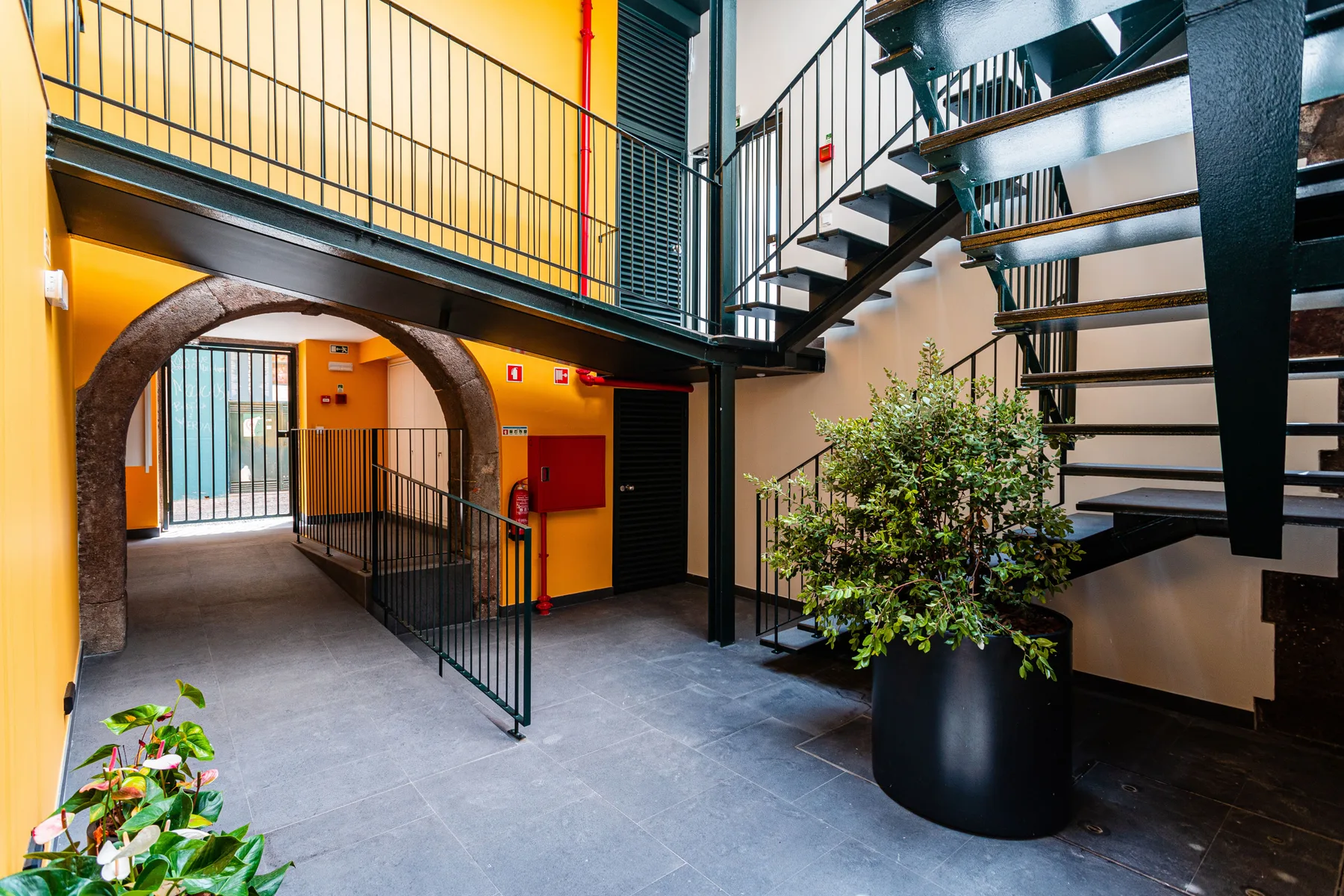 Un recibidor interior con suelo de baldosas, una escalera y plantas en macetas.