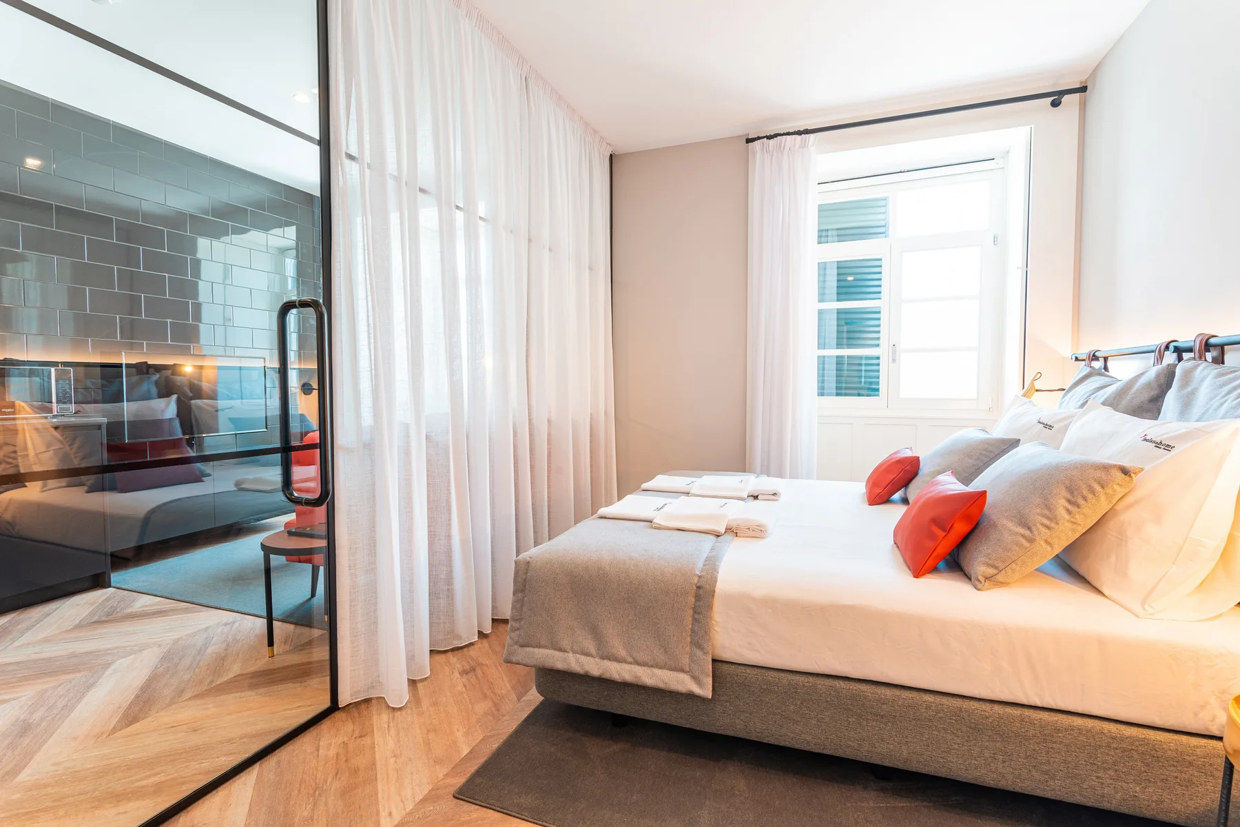 Un dormitorio luminoso con una cama grande junto a un tabique de vidrio.