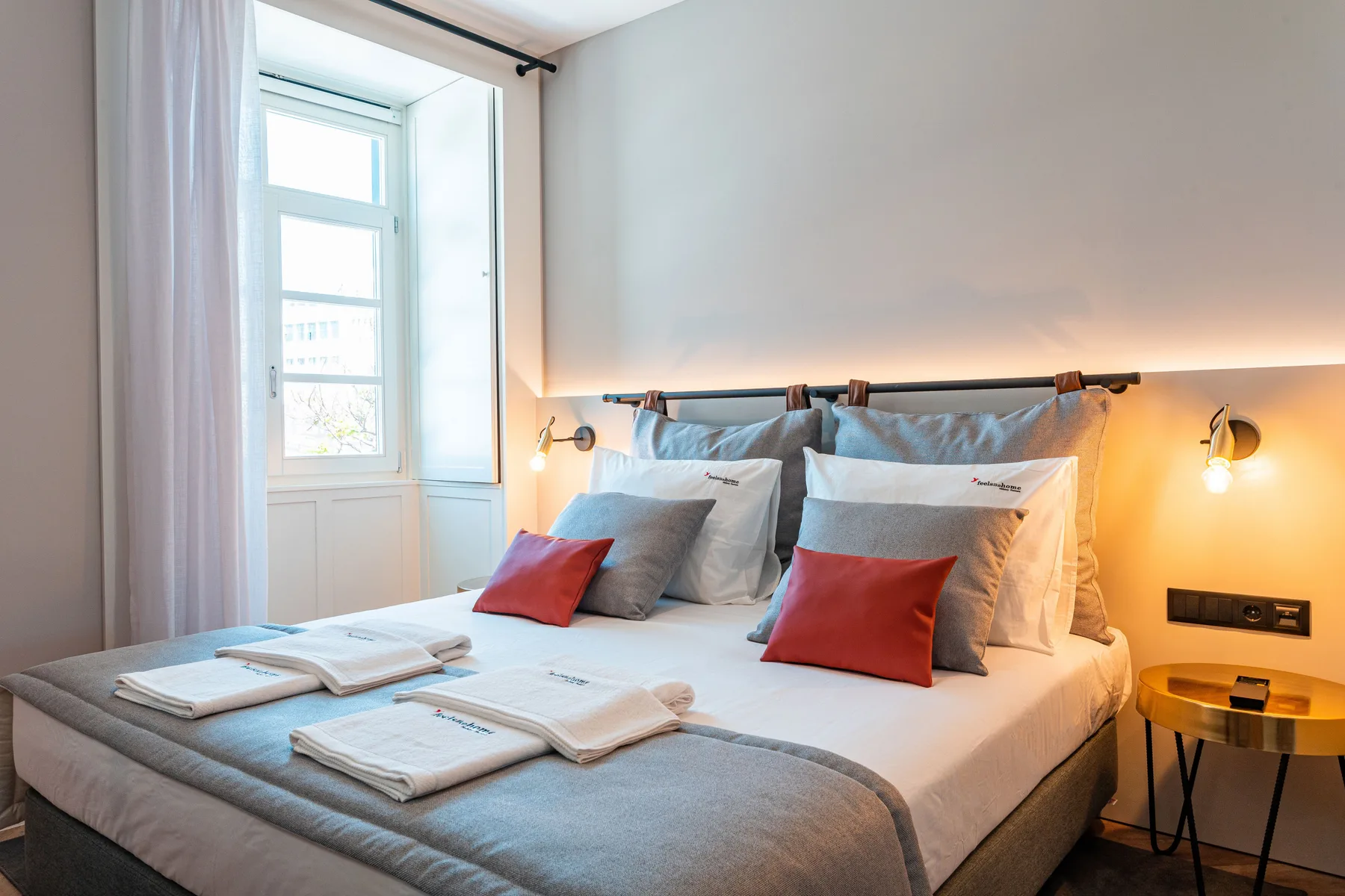 Un dormitorio con una cama bien tendida y una ventana luminosa.