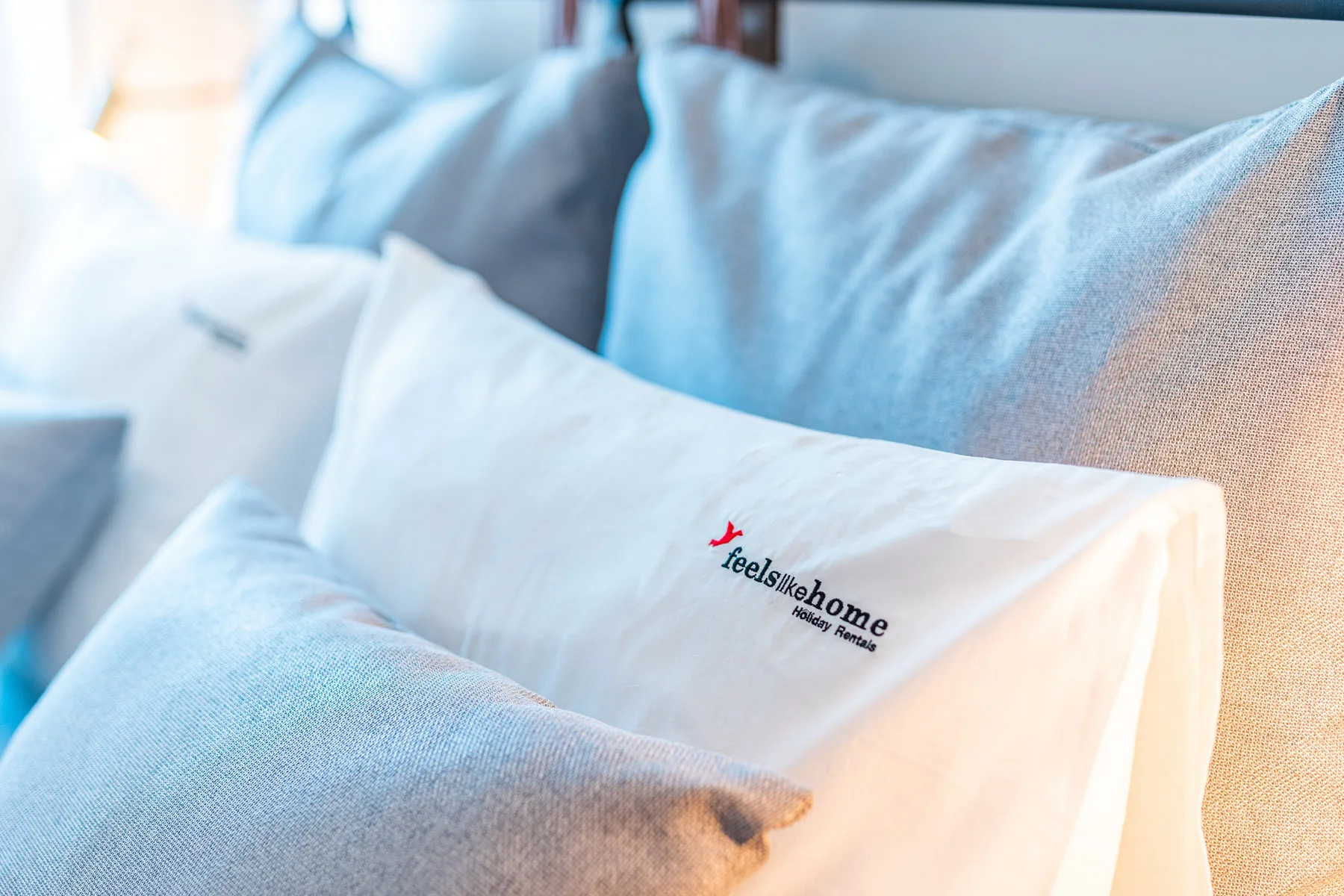 Una cama con varias almohadas, incluida una blanca con un logotipo impreso.