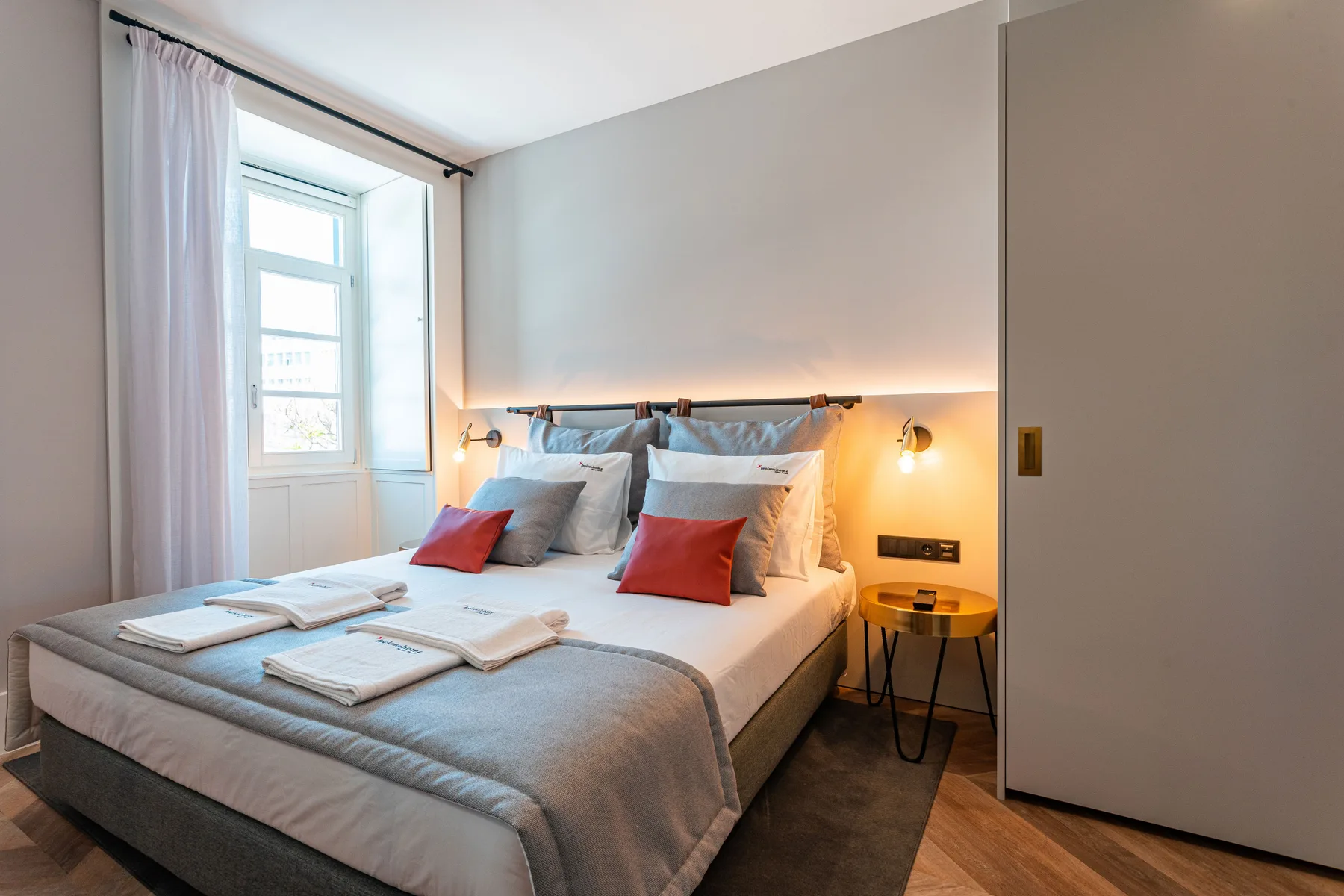 Un dormitorio con una cama bien arreglada y una ventana al lado.