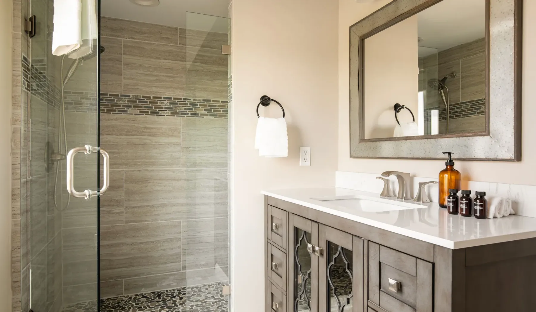 A bathroom with a glass shower and a vanity topped with a sink.