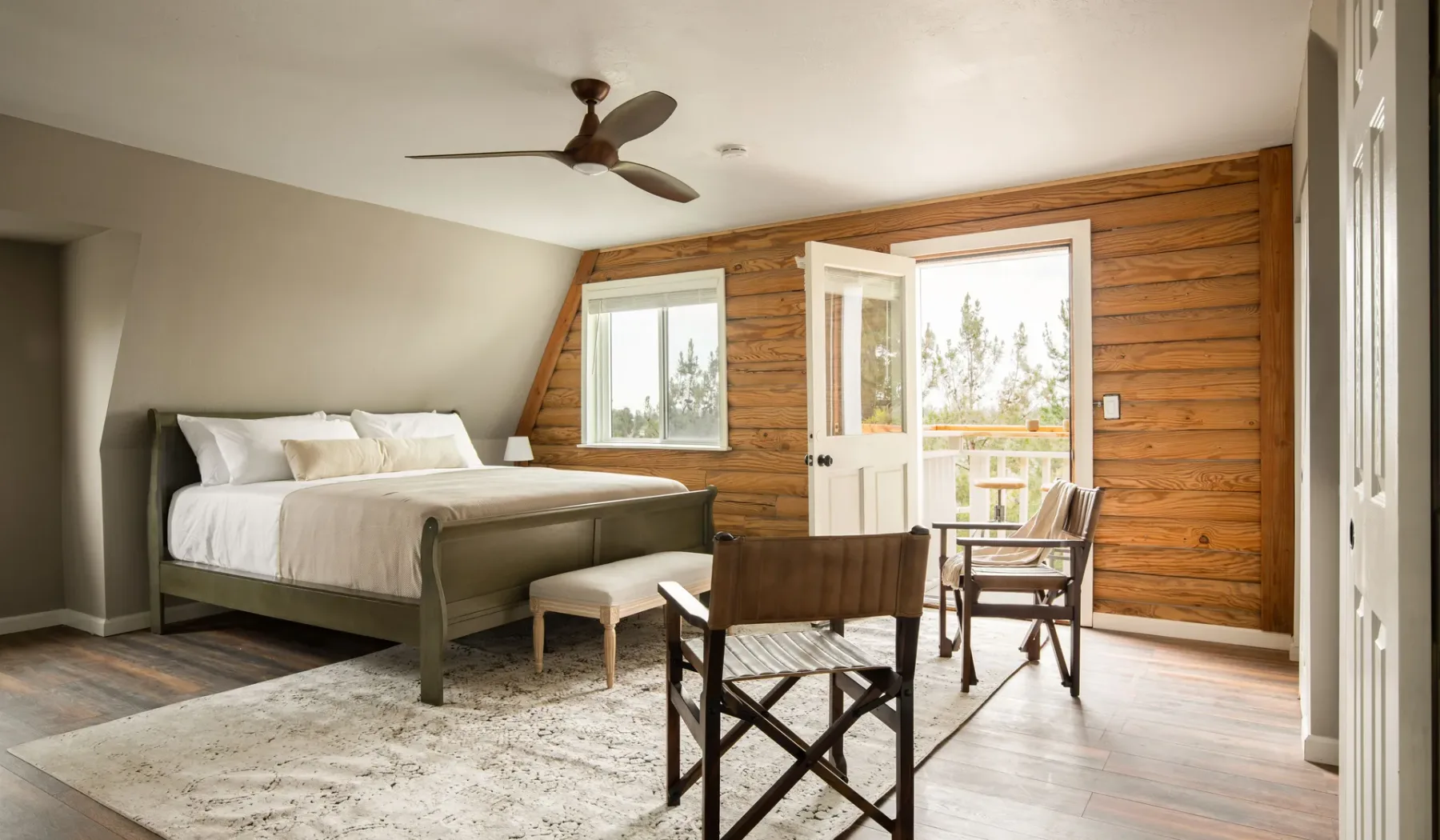 A bedroom with a bed and seating beside a wood-paneled wall.