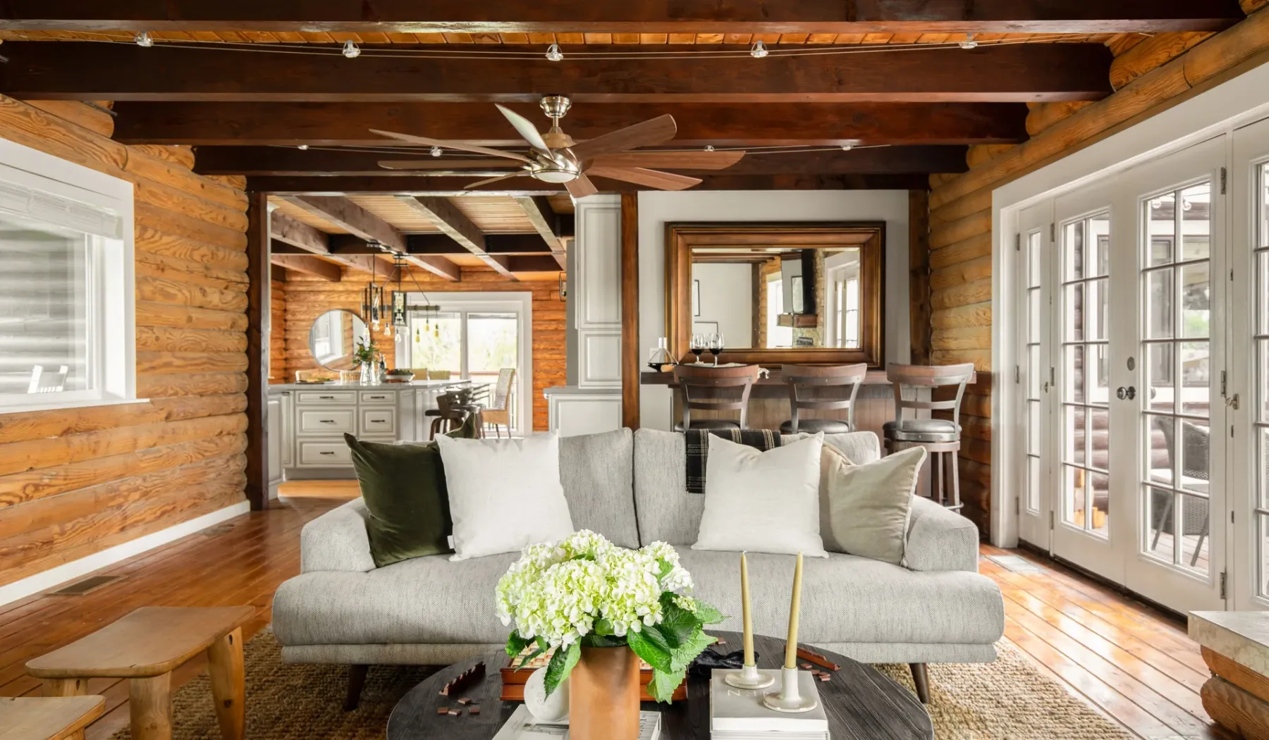 A bright living room with seating, a coffee table, and large windows.