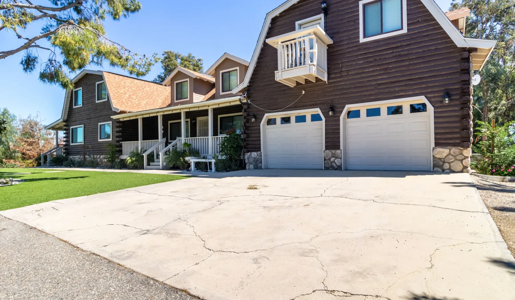 A large dark-sided house with a covered porch and two garage doors.