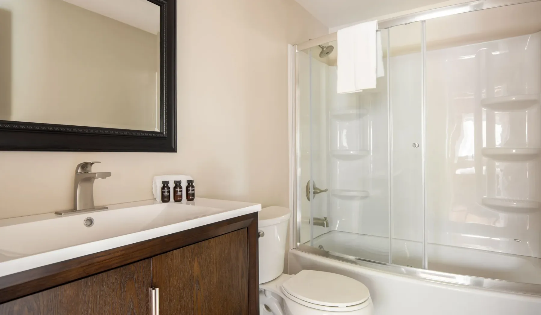 A bathroom with a sink, toilet, and glass-enclosed shower.