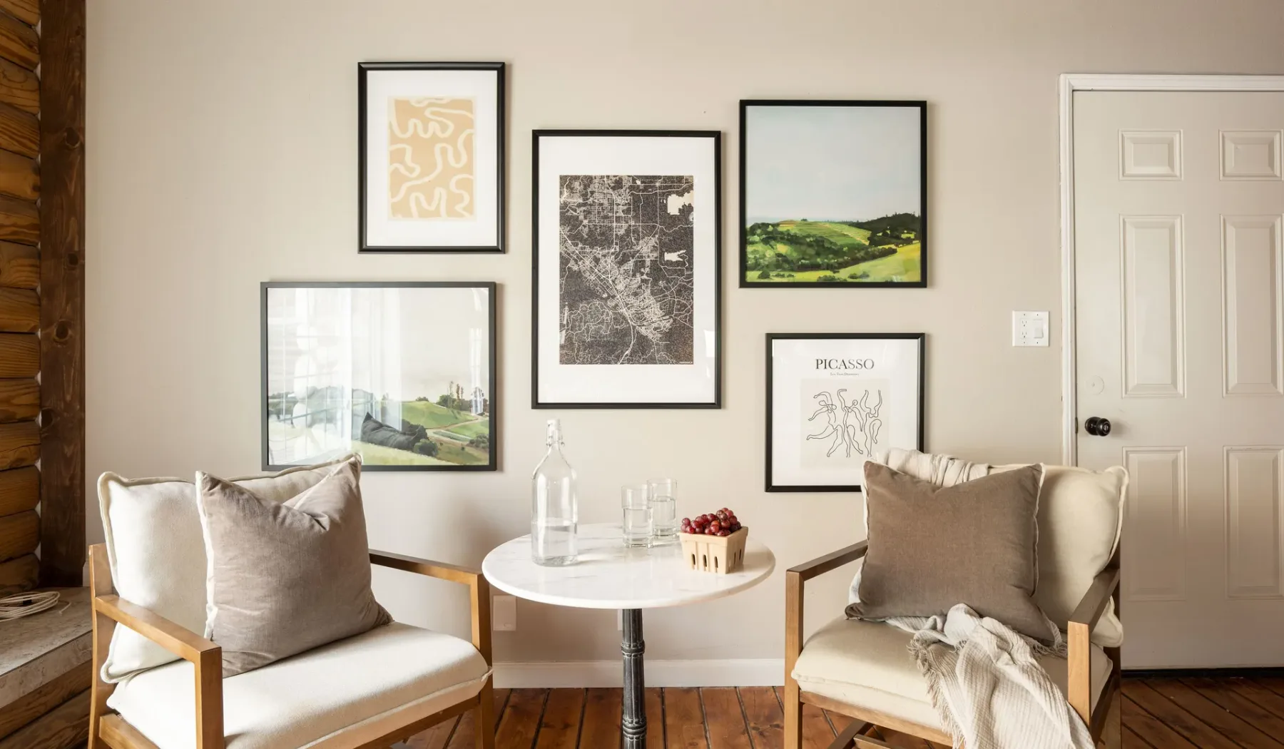 A sitting area with two cushioned chairs, a small round table, and framed artwork.