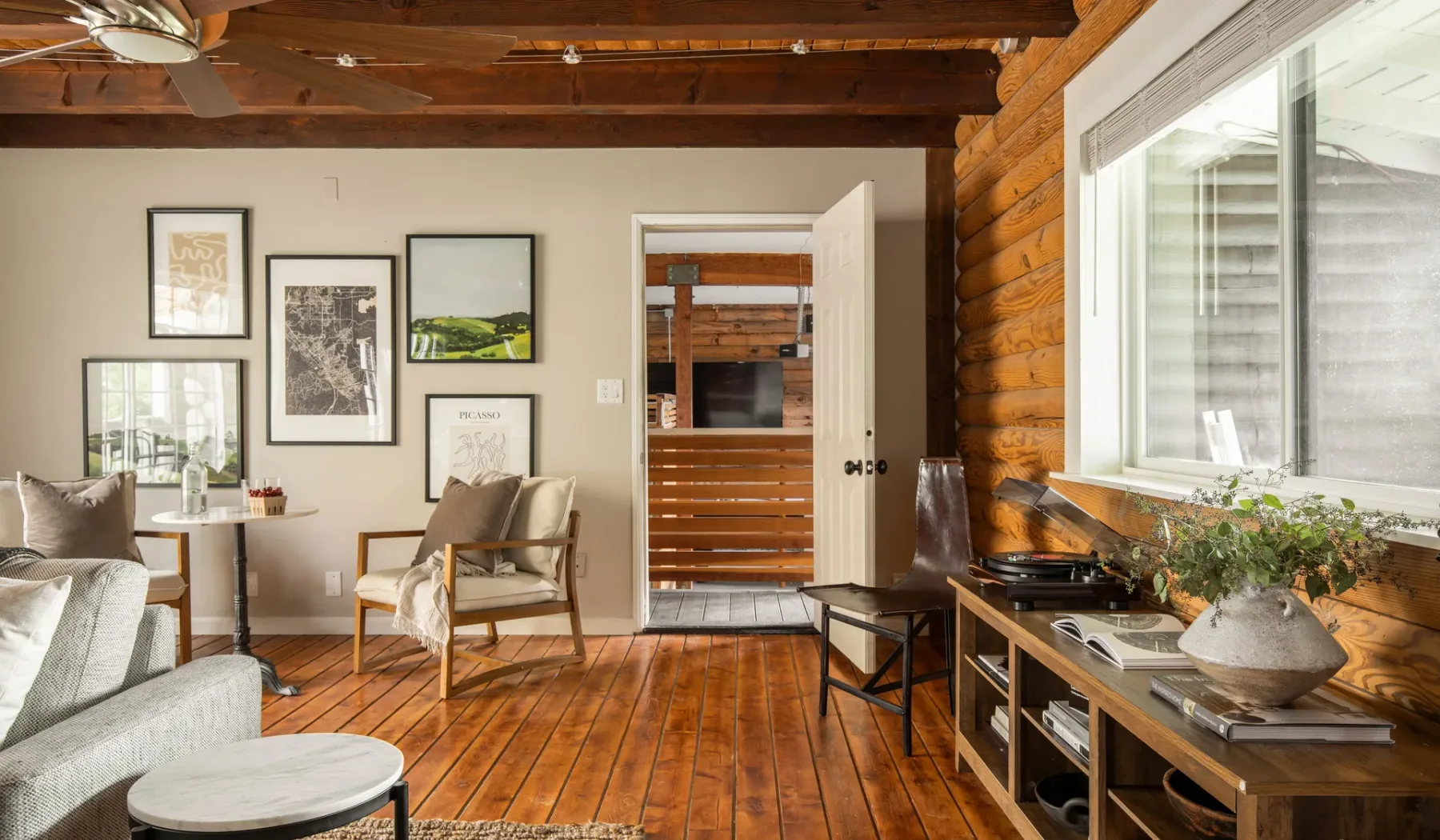 A living room with seating, framed artwork, and a wooden floor.