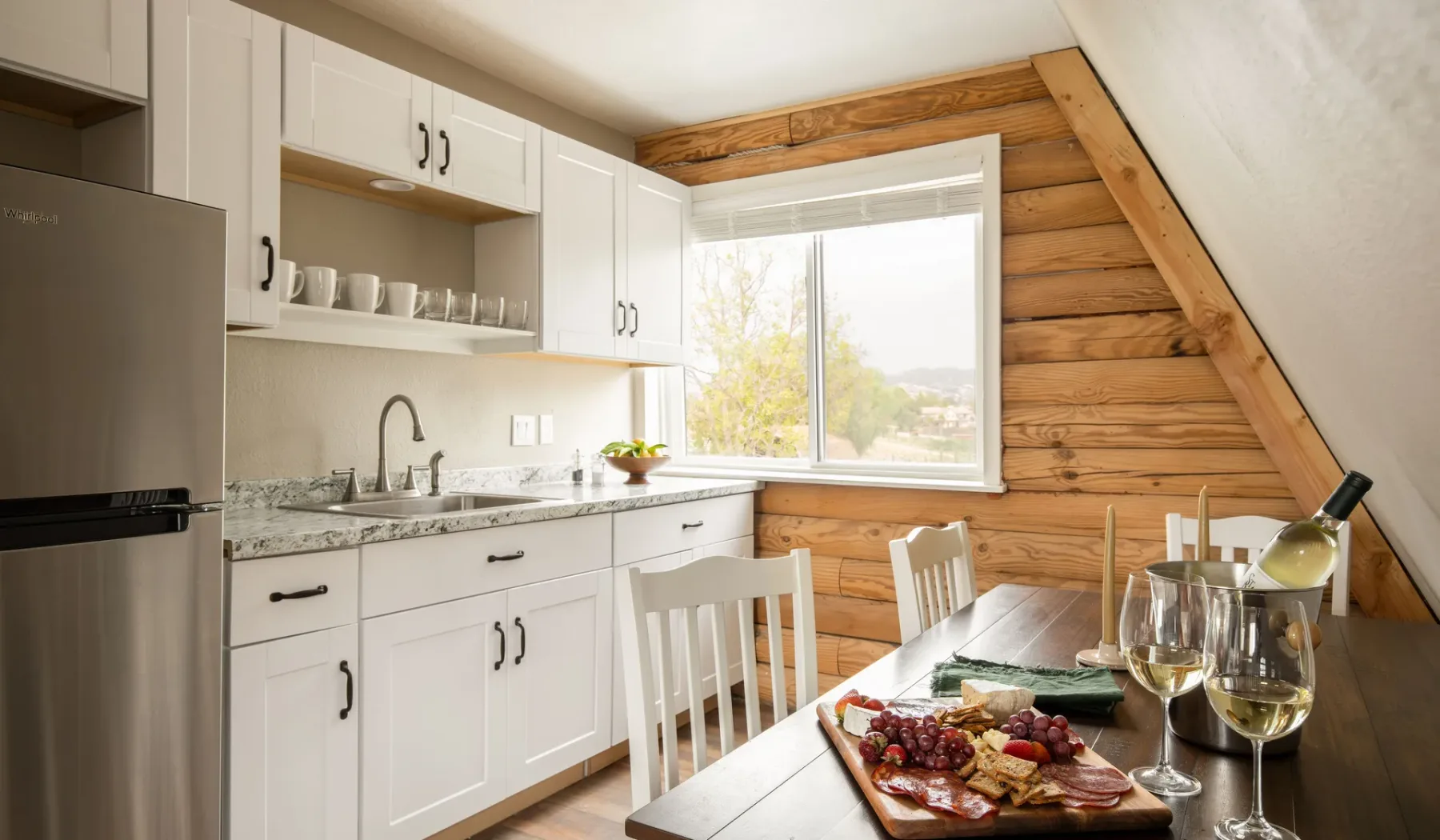 A bright kitchen with white cabinets, a counter, and a dining table.