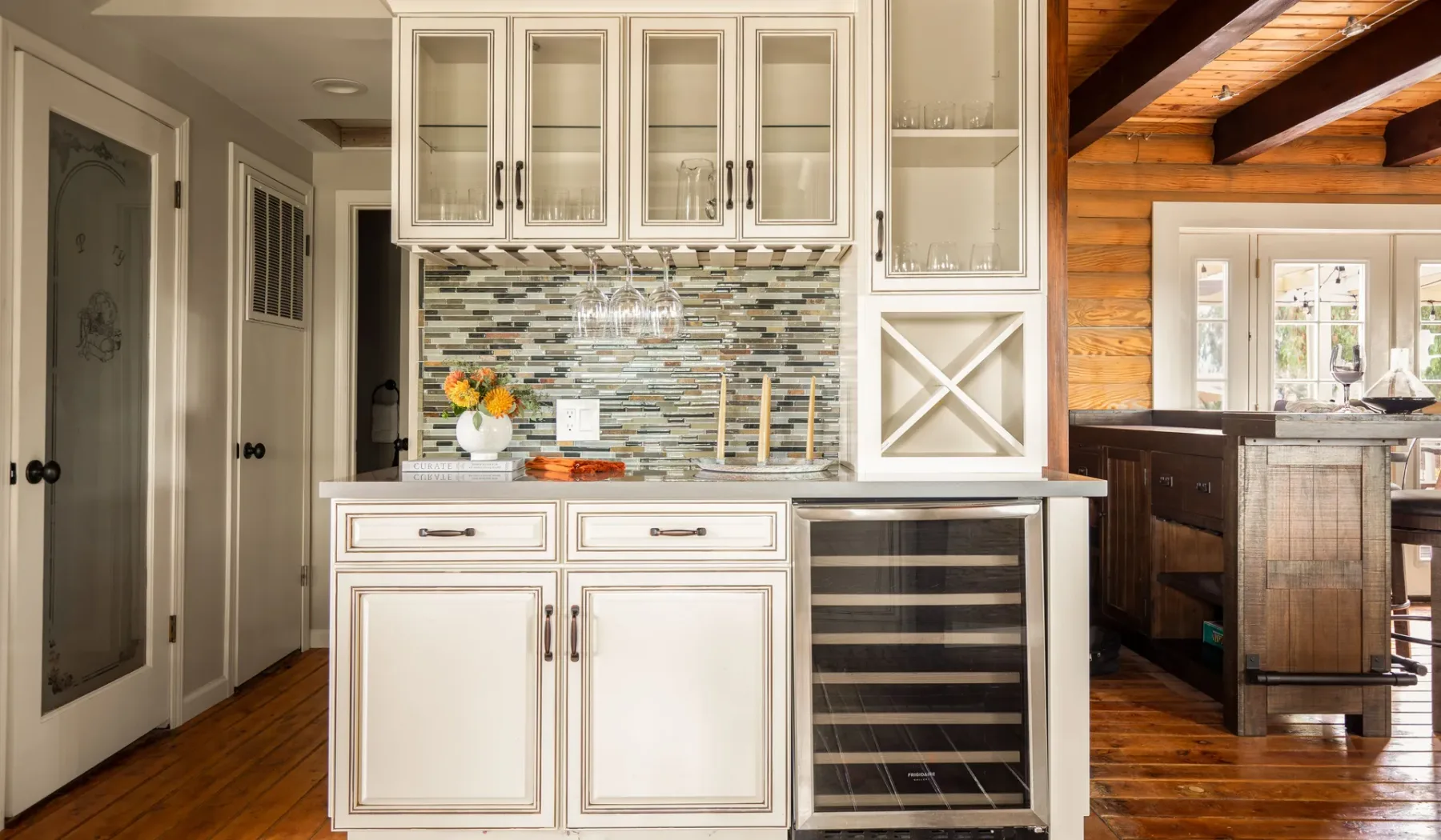 A bright kitchen with white cabinetry, a tiled backsplash, and a wine cooler.