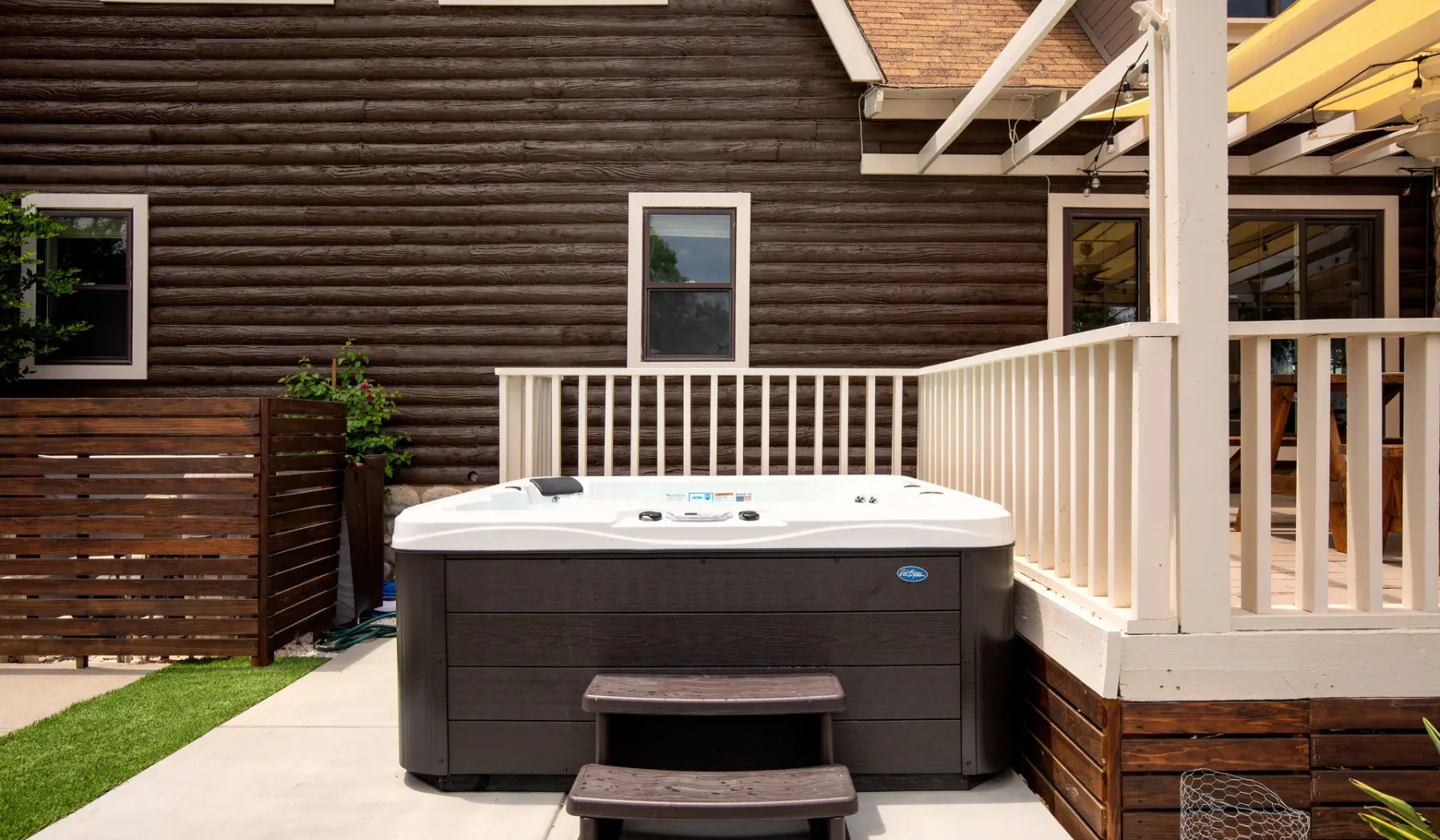An outdoor hot tub sits on a deck beside a white railing.