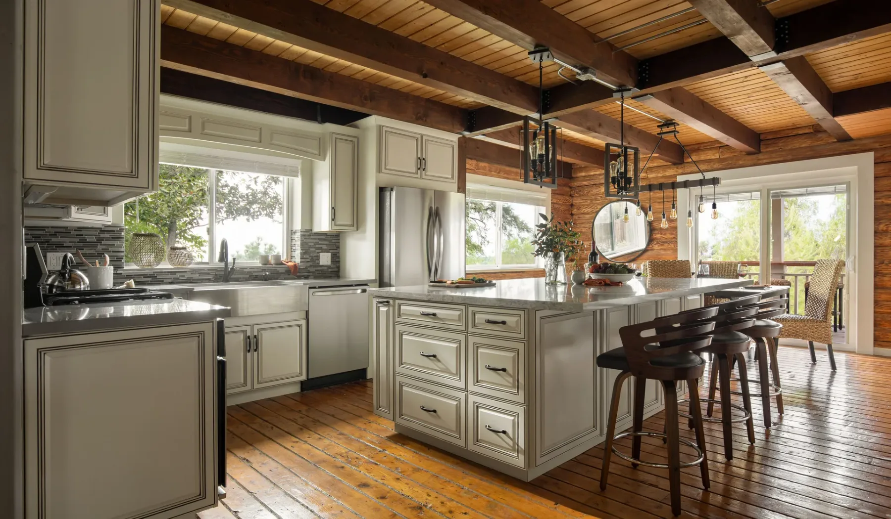 A spacious kitchen with a central island, bar seating, and exposed wooden ceiling beams.
