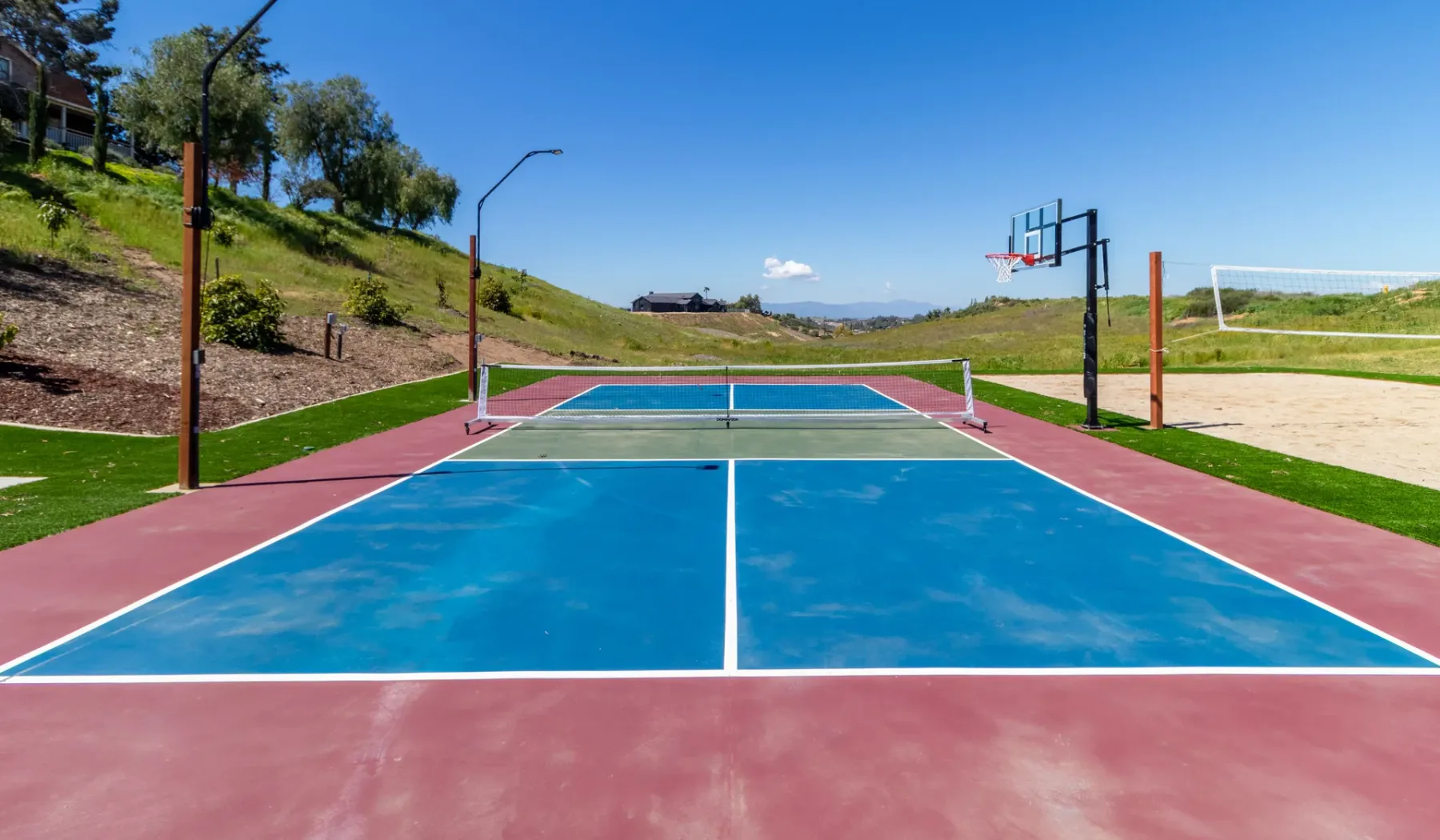 An outdoor court with blue playing surfaces and basketball hoops.