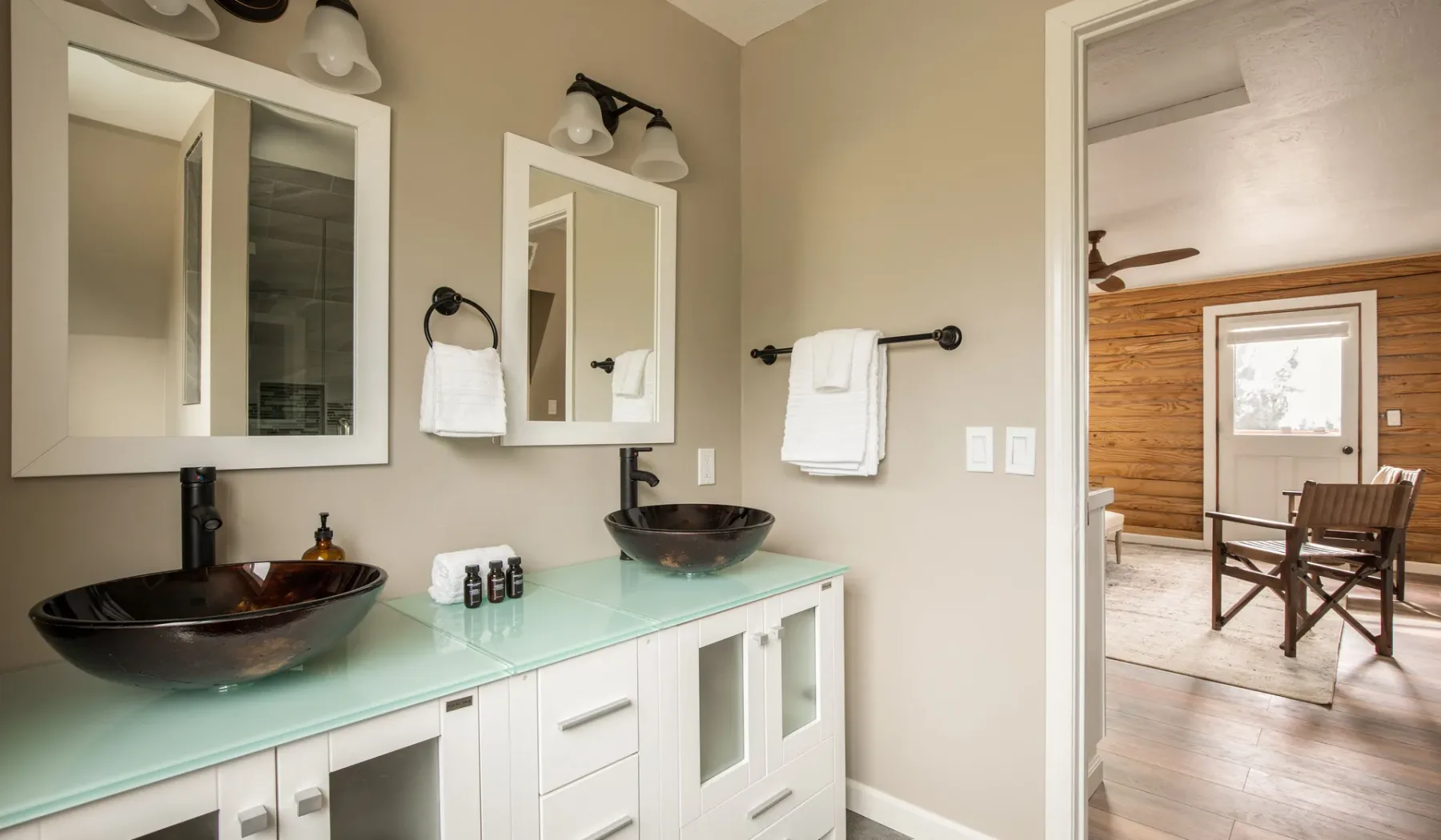 A bathroom vanity with two sinks and mirrors sits beside an open doorway.
