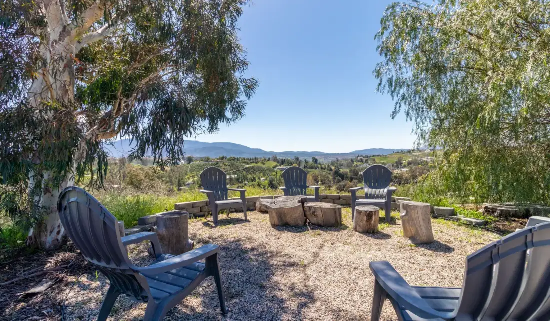 An outdoor seating area overlooks a green landscape and distant hills.
