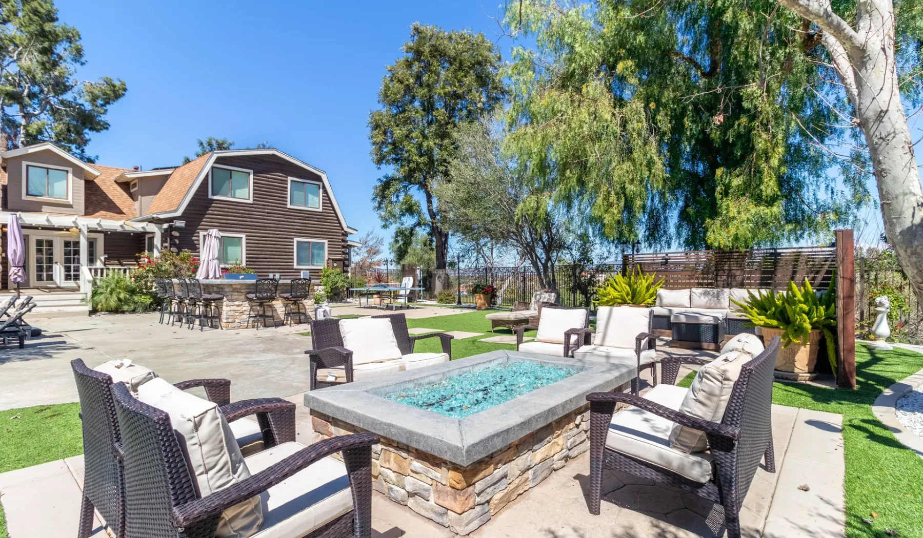 An outdoor patio with cushioned seating surrounds a square water feature.