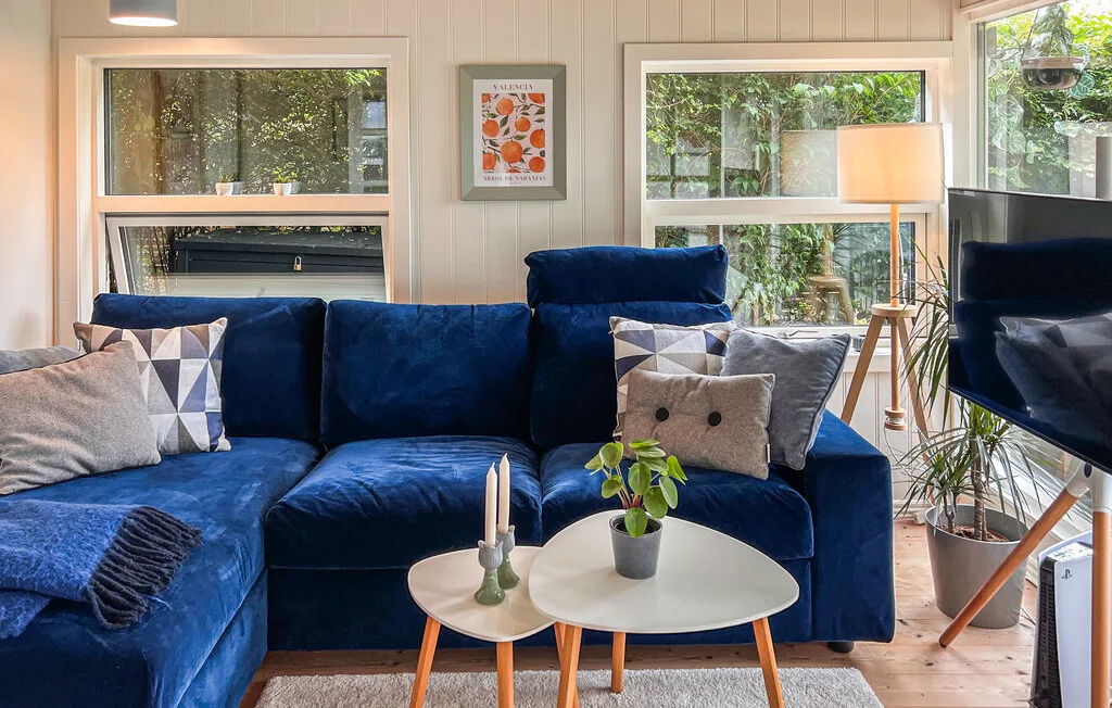 Una sala de estar con asientos azules, una mesa de centro y ventanas grandes.
