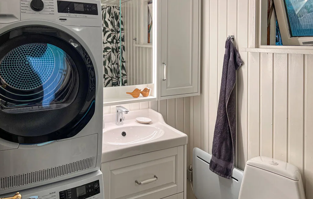 Un baño compacto con lavabo, inodoro y lavadora de carga frontal.