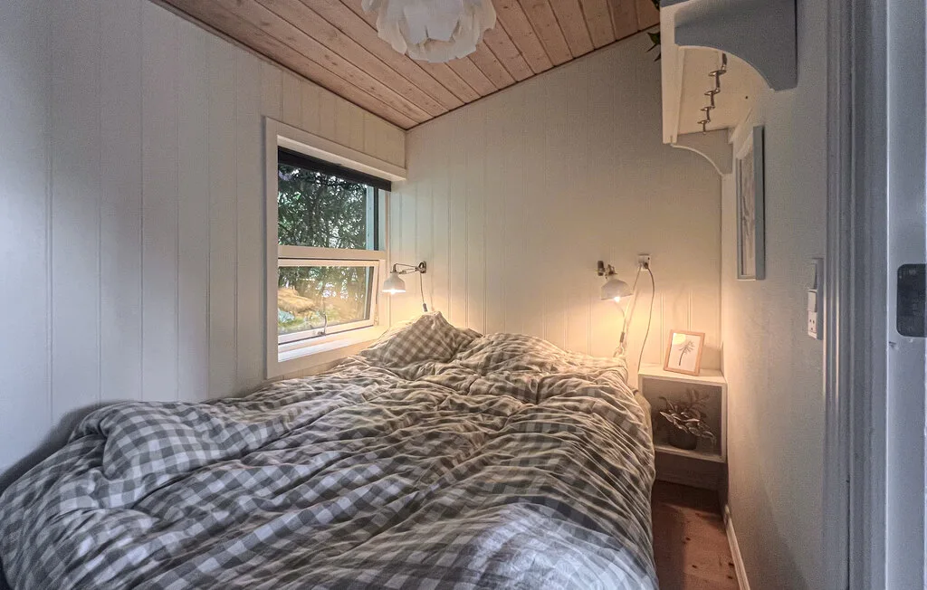 Un dormitorio pequeño con una cama junto a una ventana.