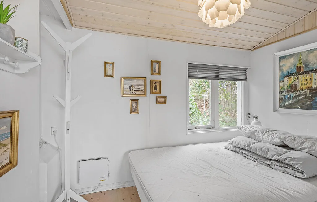 Un dormitorio luminoso con una cama bajo un techo inclinado de madera.