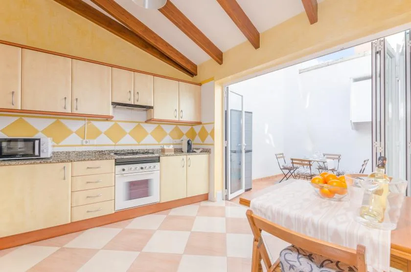Una cocina luminosa se abre a un comedor con mesa y sillas.