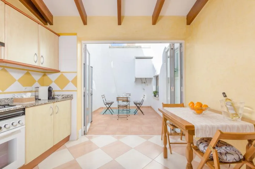 Un comedor se abre a una cocina luminosa, con una mesa de madera junto a la encimera.