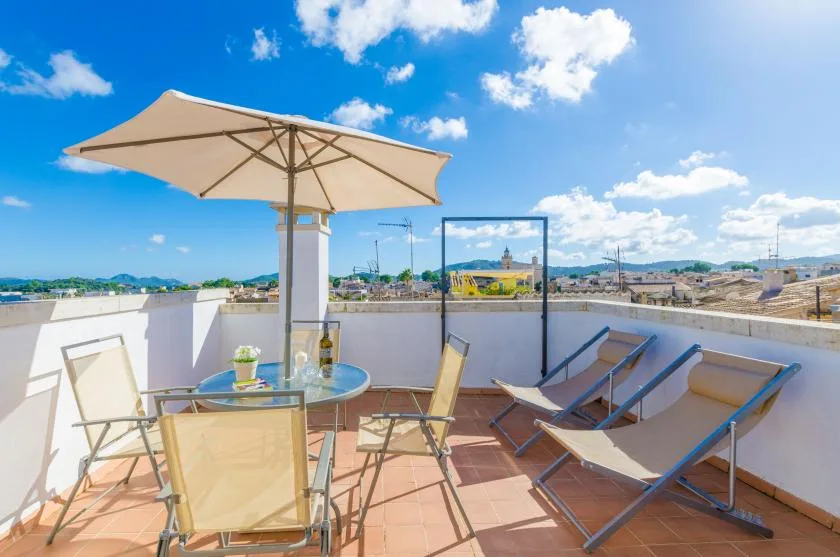 A rooftop terrace with lounge seating, an umbrella, and a city view.