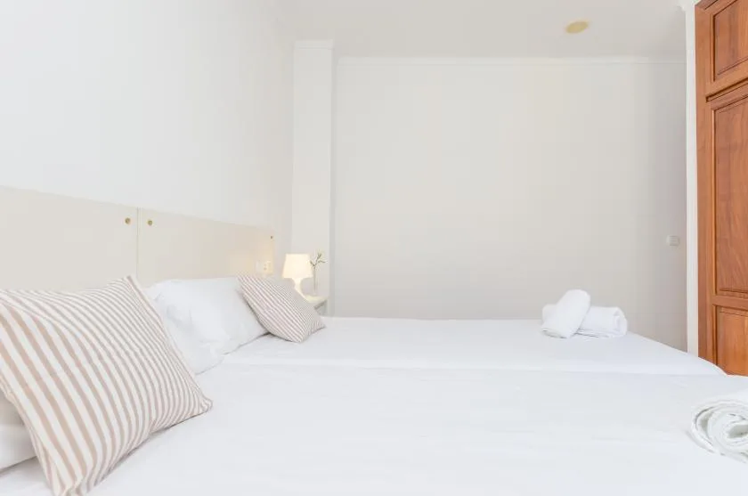Un dormitorio luminoso con una cama bien tendida y almohadas a rayas.
