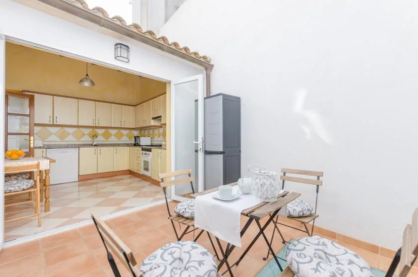 A kitchen opens onto an outdoor dining area with a table and chairs.