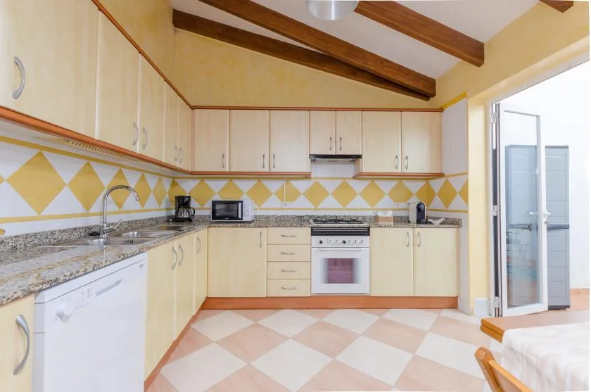 Una cocina luminosa con gabinetes claros, un salpicadero de azulejos y un horno empotrado.